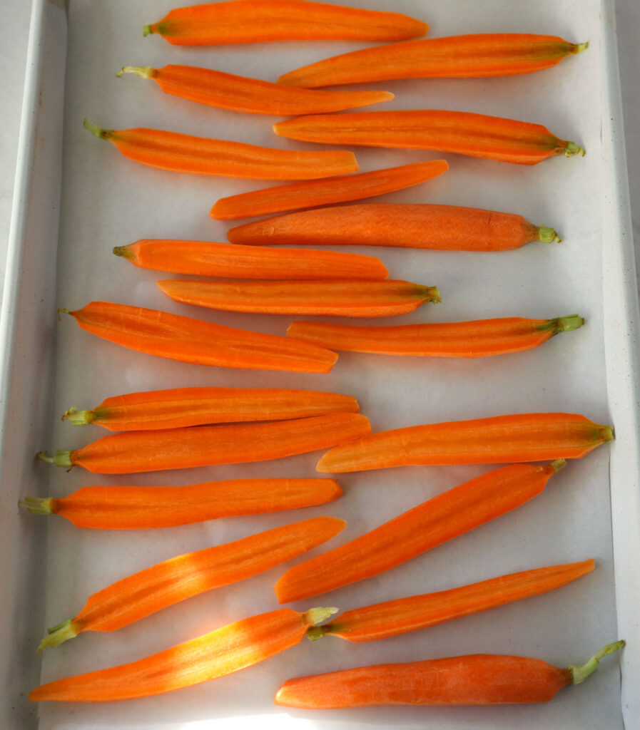 sliced carrots on a tray lined with parchment paper