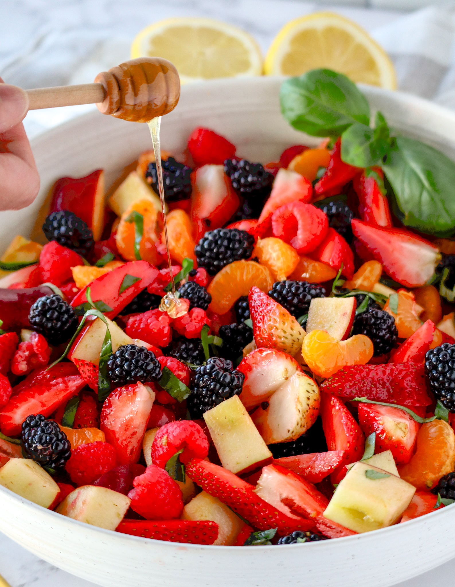 fruit salad consisting of oranges, apples, blackberries, strawberries and basil