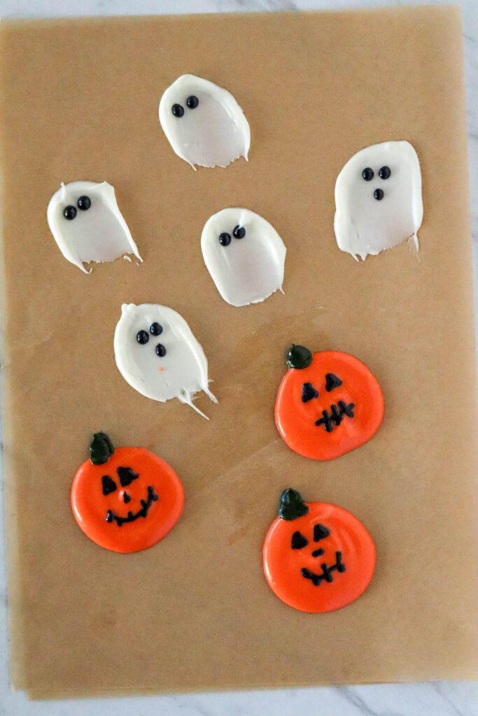 white chocolate ghosts and pumpkins on parchment paper