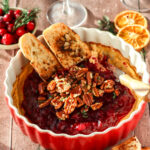 Bread that is dipped inside the Cranberry cream cheese dip with glasses of wine.