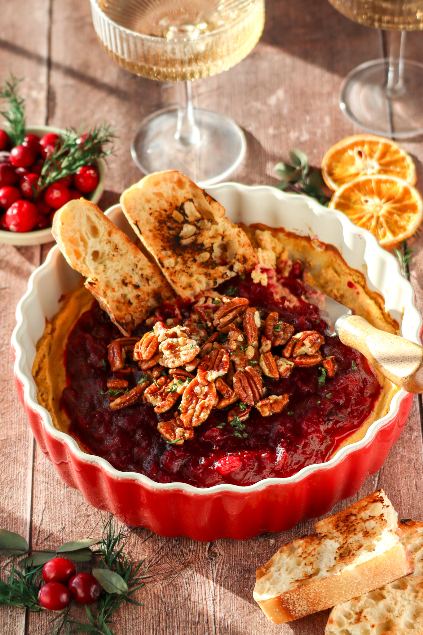 Bread that is dipped inside the Cranberry cream cheese dip with glasses of wine.